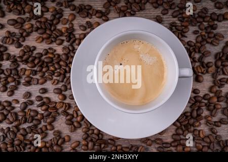 Fresh coffee crema in a white cup with coffee beans in the background Stock Photo