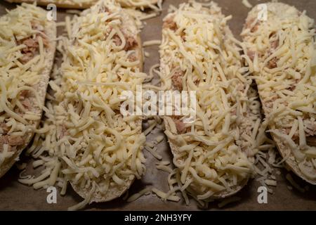 Unbaked tuna sandwich halves with cheese on the baking sheet Stock Photo