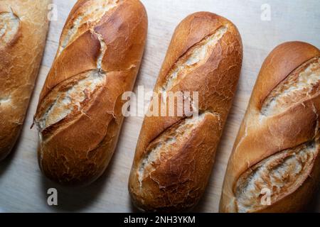 Long brown baked buns on a wooden board Stock Photo