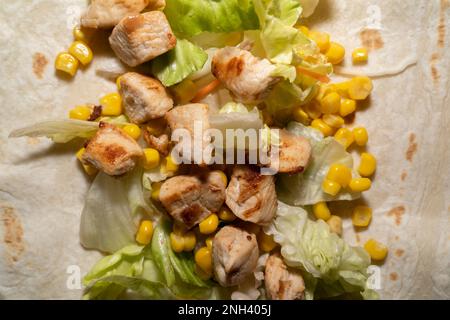 Close up of a delicious wrap with lettuce, corn and fried chicken meat Stock Photo