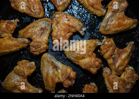 Top view of crispy chicken wings on a black baking sheet Stock Photo
