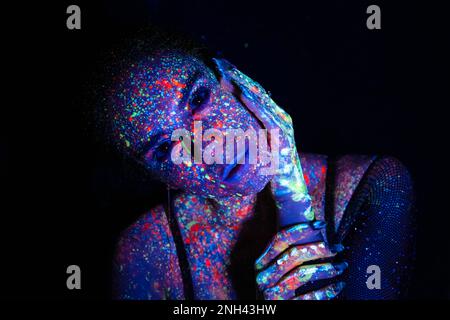Fashion model woman in neon light, portrait of a beautiful model with fluorescent makeup, artistic design of disco dancers posing in UV, colorful make Stock Photo