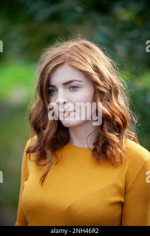 A redheaded woman wearing a mustard coloured jumper outside Stock Photo