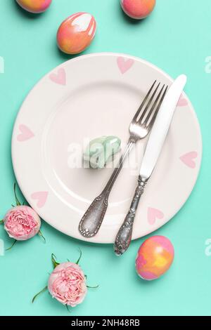 Table setting with Easter rabbit, eggs and flowers on mint background Stock Photo