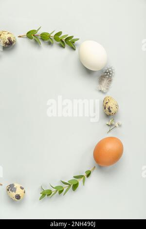 Frame made of Easter eggs and eucalyptus branches on grey background Stock Photo