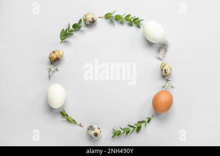 Frame made of Easter eggs and eucalyptus branches on grey background Stock Photo