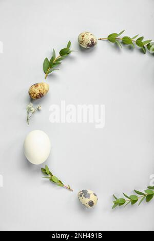 Frame made of Easter eggs and eucalyptus branches on grey background Stock Photo