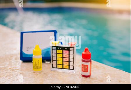 Chlorine and ph tester for swimming pools, Chlorine test kit on the edge of the pool. PH tester for pool maintenance. Water test kit for swimming Stock Photo