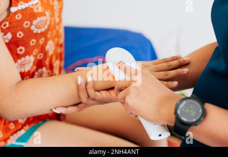 Modern laser physiotherapy on woman patient. Laser therapy used on the arm to treat pain, Close up of physiotherapist using laser therapy on patient Stock Photo
