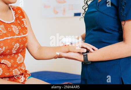 Close up of physiotherapist using laser therapy on patient arm, Modern laser physiotherapy on patient. Laser therapy used on the arm to treat pain Stock Photo