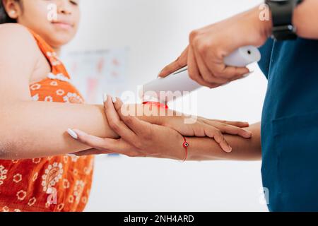 Laser therapy used on the arm to treat pain, Close up of physiotherapist using laser therapy on patient arm. Modern laser physiotherapy on woman Stock Photo
