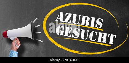 hand of man holding megaphone or bullhorn against blackboard with text AZUBIS GESUCHT, German for apprentices or trainees wanted Stock Photo
