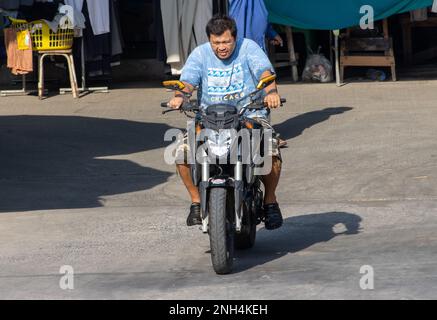 SAMUT PRAKAN, THAILAND, FEB 13 2023, A man rides a motorcycle at market Stock Photo