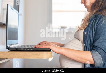 pregnant woman working on laptop from home Stock Photo