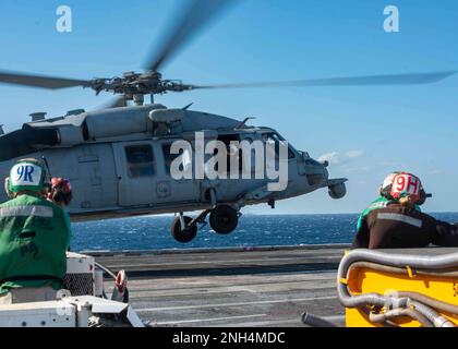 221213-N-UF592-1059 PHILIPPINE SEA (Dec. 13, 2022) Sailors observe as an MH-60S Sea Hawk, attached to the Golden Falcons of Helicopter Sea Combat Squadron (HSC) 12, takes off from the flight deck of the U.S. Navy’s only forward-deployed aircraft carrier, USS Ronald Reagan (CVN 76), in the Philippine Sea, Dec. 13. HSC 12, originally established as Helicopter Anti-Submarine Squadron (HS) 2 on March 7, 1952, is the oldest active operational Navy helicopter squadron. Ronald Reagan, the flagship of Carrier Strike Group 5, provides a combat-ready force that protects and defends the United States, an Stock Photo