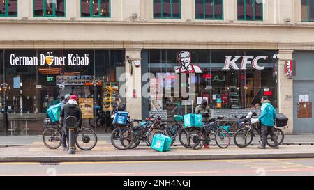 Deliveroo riders with bikes waiting outside Food Outlets in Manchester UK Stock Photo