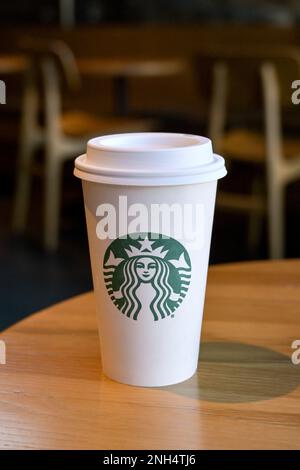 Austin, Texas - February 2023: Paper cup with Starbucks logo on a table in one of the company's chain of coffee shops Stock Photo