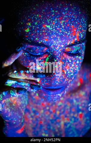 Fashion model woman in neon light, portrait of a beautiful model with fluorescent makeup, artistic design of disco dancers posing in UV, colorful make Stock Photo