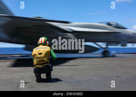 PACIFIC OCEAN (June 21, 2022) ) Aviation Boatswain’s Mate (Equipment) 2nd Class Kayla Pettit, from Charlotte, N.C., signals an F/A-18E Super Hornet, assigned to the “Vigilantes” of Strike Fighter Squadron (VFA) 151, as it launches from the flight deck of the Nimitz-class aircraft carrier USS Abraham Lincoln (CVN 72). Abraham Lincoln Strike Group is underway conducting routine operations in the U.S. 3rd Fleet. Stock Photo