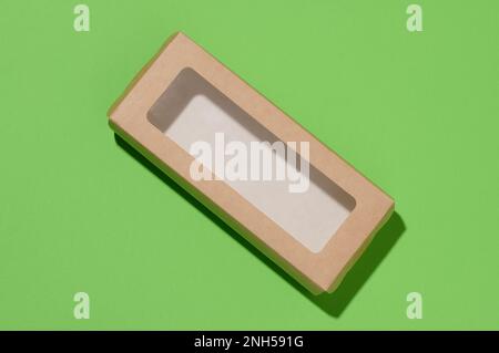 Rectangular cardboard box with a transparent plastic lid on a green background, top view Stock Photo