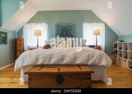 Queen size bed with pine wood nightstands, chest in upstairs master bedroom with wide pine wood plank floorboards inside old circa 1830 home. Stock Photo