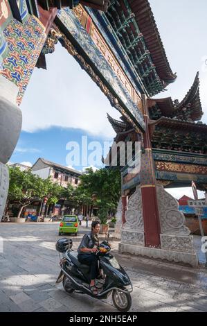 A motorcyclist passes through a traditional gate in the Chinese city of Jianshui in Yunnan province Stock Photo
