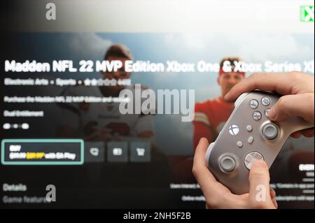 New york, USA - February 20, 2023: NFL american football game on computer console with xbox joystick in hand close up view Stock Photo
