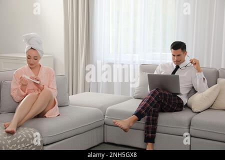 Man working on laptop while his wife relaxing in living room. Stay at home concept Stock Photo
