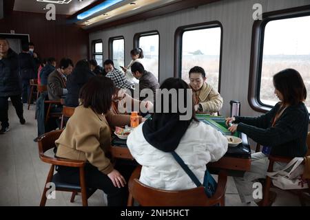 XI'AN, CHINA - FEBRUARY 18, 2023 - Passengers play mahjong on a bus in Xi 'an, Shaanxi province, China, Feb 18, 2023. A customized cultural train with Stock Photo