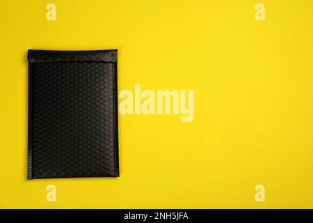 Padded envelope with bubble wrap on yellow background, top view. Space for text Stock Photo