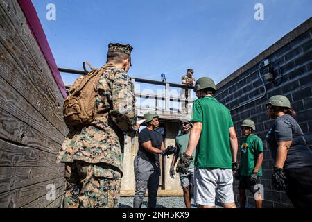 A Marine instructor observes coaches and staff members from Norfolk State University located in Norfolk, Virginia.  The participants must work as a team to complete each of the assigned tasks while executing the Leadership Reaction Course at the Officer Candidate School at Marine Corps Base Quantico, Virginia, on July 18, 2022. The coaches, athletic staff, and directors joined forces with Marine Corps Recruiting Command as part of their annual retreat designed to enhance their bond, leadership, and problem-solving skills. Stock Photo