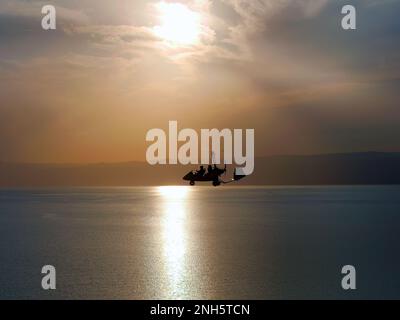 Silhouette of Gyrocopter, fun fly, aero sports, skydive, Roto craft, Gyroplane flying against sunset light over the Dead Sea, flying in the sky, dawn Stock Photo