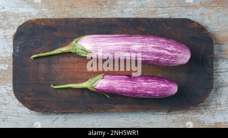 eggplants or brinjals, also known as aubergine, common vegetable on a wooden cutting board, taken straight from above with copy space Stock Photo