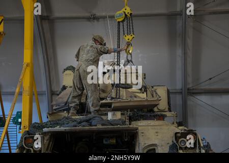 U.S. Army Spc. Michael Nichols, a mechanic assigned to Apache Troop, 4th Squadron, 10th Cavalry Regiment, 3rd Armored Brigade Combat Team, 4th Infantry Division, uses a crane to remove the engine cover of an M2A3 Bradley Fighting Vehicle during annual services at Trzebień, Poland, July 18, 2022. The 3/4 ABCT is among other units assigned to the 1st Infantry Division, proudly working alongside NATO allies and regional security partners to provide combat-credible forces to V Corps, America's forward-deployed corps in Europe. Stock Photo