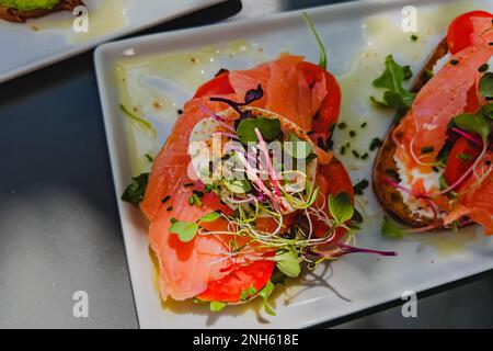 Toast with salmon, tomato, egg and micro green on the white plate Stock Photo