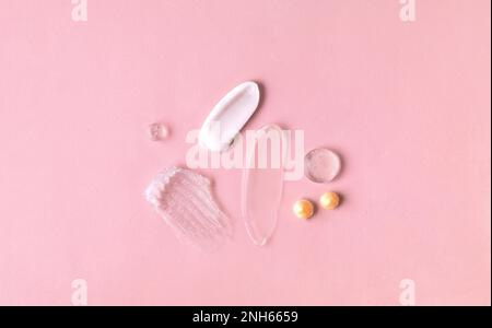 Swatches from various cosmetic products, drops of lotion, smears of creams, gels and scrubs on pink background Stock Photo