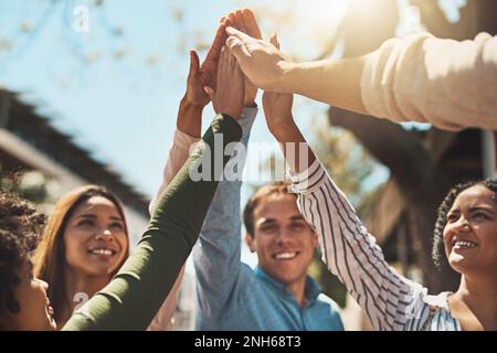 Heres to a awesome day ahead of us. a group of cheerful young friends forming a huddle and giving each other a high five outside during the day. Stock Photo