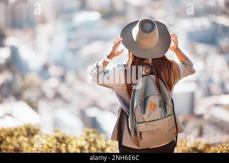 Back view of woman looking at cityscape through glass window of ...