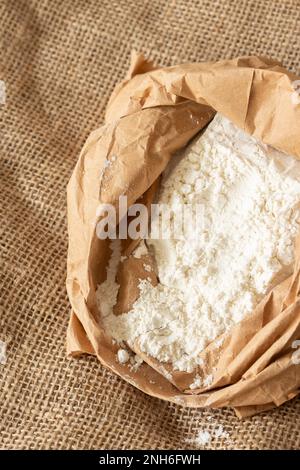 Plain white flour in a brown paper bag on hessian sack cloth. Eco friendly biodegradable recycle packaging Stock Photo