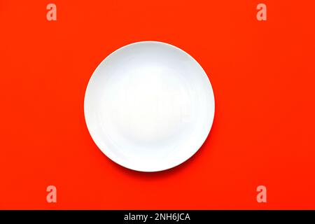 White empty plate with blank surface on bright red backdrop, top view Stock Photo