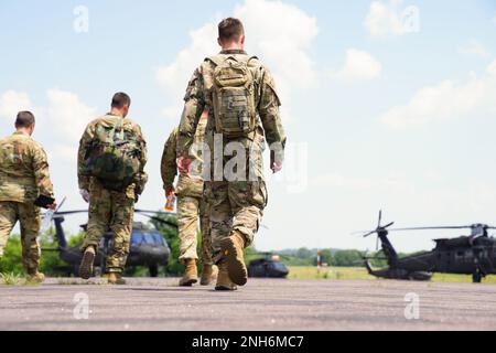 U.S. Soldiers assigned to the Pennsylvania National Guard walk towards a UH-60 Black Hawk during their Annual Training at Ft. Indiantown Gap, July 20, 2022.  Flights are a common occurrence at the Gap and help crews and pilots maintain critical skills needed for missions both domestic and abroad. Stock Photo