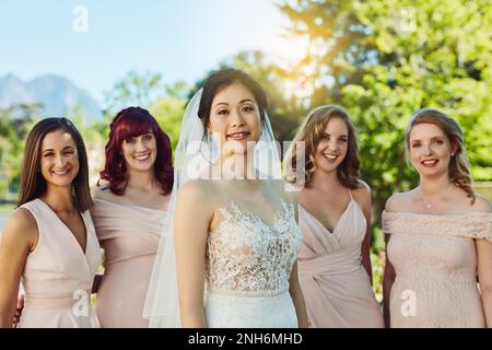 Best friends make the best bridesmaids. Portrait of a cheerful young bride and her brides maids standing together outside during the day. Stock Photo
