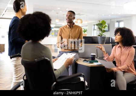 African american businesswoman on wheelchair and diverse people in office talking Stock Photo