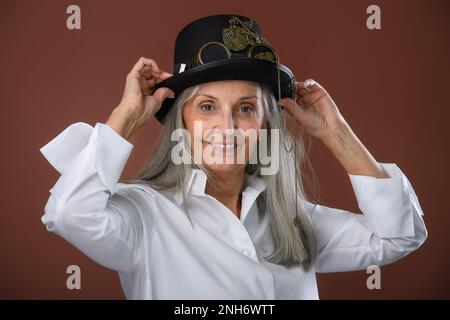 Portrait of happy senior woman in shirt and hat, studio shoot. Stock Photo