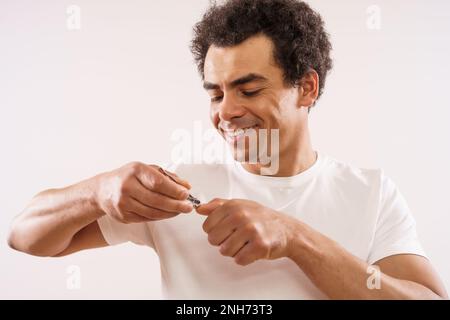 Handsome mixed race adult man is cutting his fingernails. Stock Photo