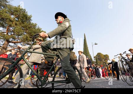 Antique Bicycle Adventure: Carnival-goer Rides a Penny Farthing Through the Crowds Stock Photo