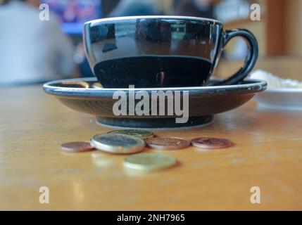 the increase in price of a cup of coffee, coins on the table Stock Photo