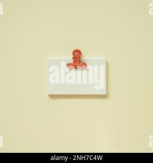 Blank white memo paper with coral clip on yellow desk background. top view, copy space Stock Photo