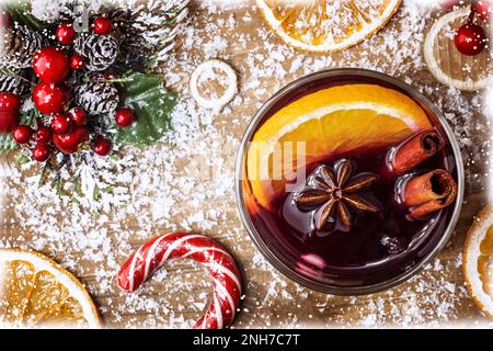 Christmas mulled in a glass, red wine with spices and fruits oranges on a wooden rustic table with fir branches new year. Traditional hot christmas dr Stock Photo