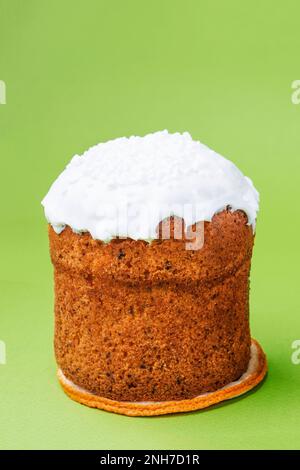 Easter cake, with dried fruits, raisins under white sugar icing with coconut, isolated on green background. Baking concept, traditional easter treats. Stock Photo